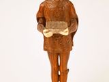 figurine en bois représentant un homme tenant un livre, posée sur une surface blanche