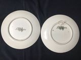 two white plates with black writing on them on a black table