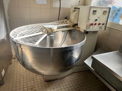 un grand saladier en métal dans une cuisine, avec un batteur électrique posé sur le plan de travail