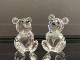 figurines en cristal représentant deux oursons assis sur une surface noire