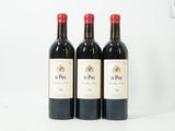 trois bouteilles de vin rouge sont alignées sur une surface blanche