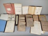 Plusieurs vieux livres sont posés sur une table, recouverts de feuilles de papier.