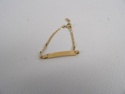 un bracelet en or orné d'une barre, posé sur une surface blanche