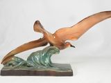 a statue of a bird that is flying over a wave