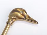 a gold colored bird head on a cane on a white surface
