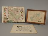 two framed maps and a picture of a map on a table