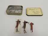 two fishing lures and a tin on a table