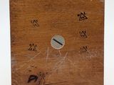 a small wooden box with a metal button on it