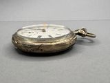 a silver pocket watch with a chain on a table