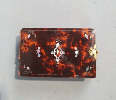 un petit portefeuille en écaille de tortue avec un fermoir doré