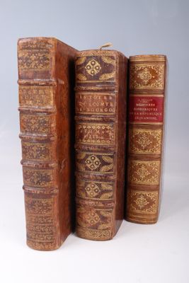 several old books are stacked on top of each other on a white surface
