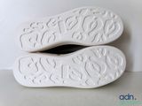 pair of white shoes on a white surface with a white background