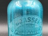 une vieille bouteille en verre bleu avec une poignée en métal, posée sur une table
