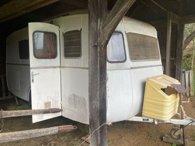 une remorque blanche garée sous une structure en bois