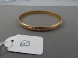 a gold bracelet with a tag on it on a table