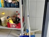 a mop and bucket on the floor next to a shelf