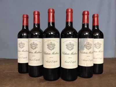 six bottles of red wine are lined up on a wooden table