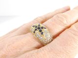 a woman ' s hand holding a gold ring with black and white stones