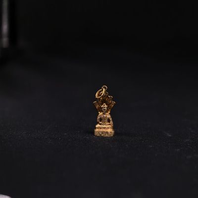 une petite statue en or représentant une personne assise sur une surface noire