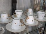 de nombreuses tasses et soucoupes posées sur une étagère en verre