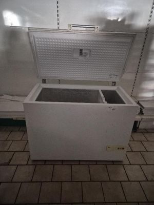 a white chest freezer sitting in the middle of a tiled floor