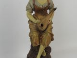 figurine of a woman sitting on a rock with a guitar