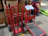 un diable rouge posé à côté d'une pile de cartons
