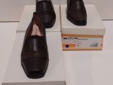 deux paires de chaussures noires posées sur des cartons, sur une surface blanche