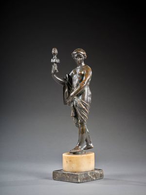 une statue en bronze représentant un homme tenant un oiseau, posée sur un socle en marbre