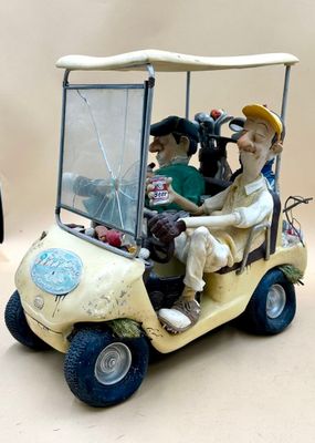 toy figurines of people riding in a golf cart on a table