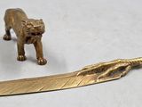 figurine en laiton représentant un tigre et une plume posée sur une table