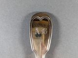 silver spoon with a face on it sitting on a white surface