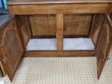 a wooden cabinet with a white cushion on the bottom of it