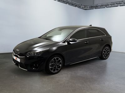 La voiture noire est garée dans une grande pièce aux murs blancs.