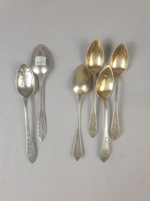 quatre cuillères en argent et une cuillère en argent posées sur une surface blanche