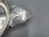 a silver bowl with a spoon in it sitting on a table