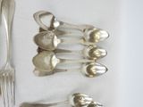 five spoons and a fork on a white table