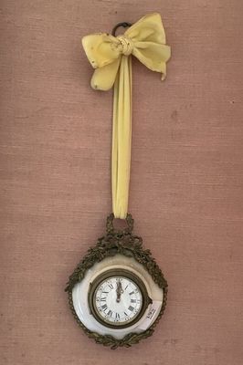 une horloge accrochée au mur, ornée d'un nœud jaune