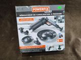 La boîte d'une perceuse Powerfix est posée sur une surface marron
