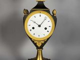 une horloge ancienne ornée de motifs dorés et noirs, posée sur un socle