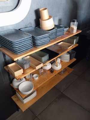 une étagère sur laquelle sont posés de la vaisselle et des tasses, dans une cuisine
