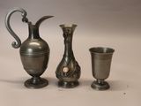 trois vases en argent posés l'un à côté de l'autre sur une table
