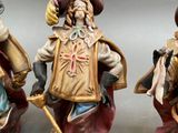three figurines of men dressed in medieval clothing and holding swords