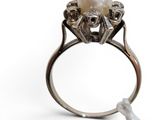 a close up of a ring with a pearl in it on a white background