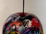 une pomme colorée, ornée de graffitis, posée sur une table