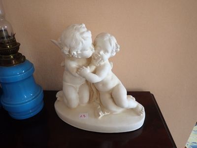 une petite statue représentant un garçon et une fille assis sur une table