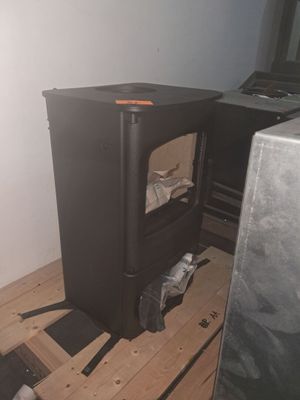 a black stove sitting on a wooden floor in the corner of a room