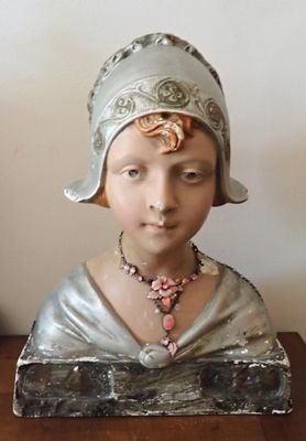 une statue représentant une femme coiffée d'un chapeau, posée sur une table