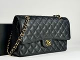 a black chanel bag with a gold chain and a black box