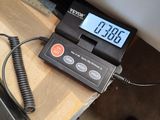 a digital scale sitting on a table with a person standing next to it